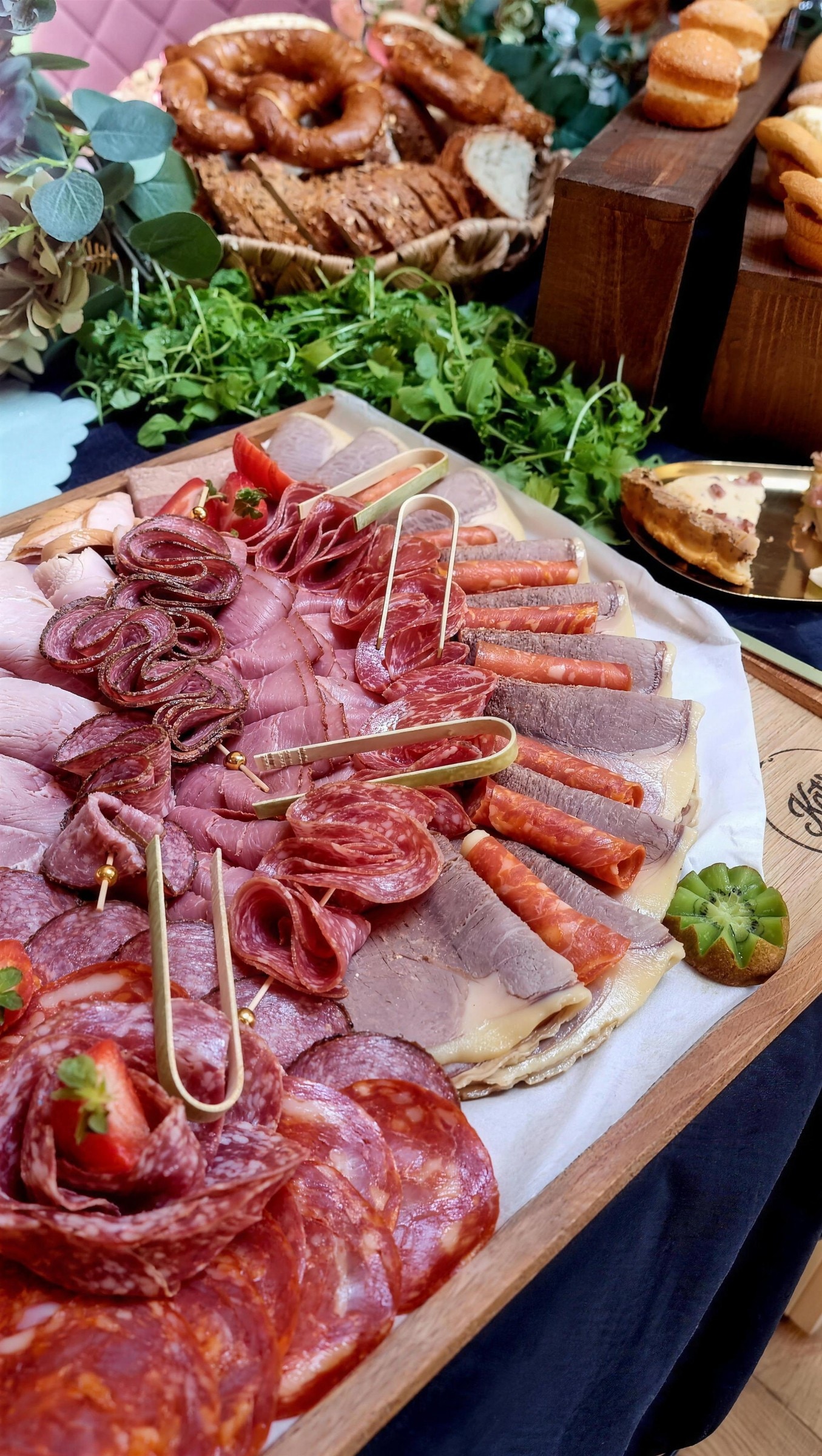 Platter of folded cured meats, salami, roast beef and pastrami with strawberries and kiwi